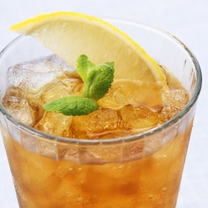 May include: A glass of iced tea with ice cubes, a lemon wedge, and a sprig of mint.