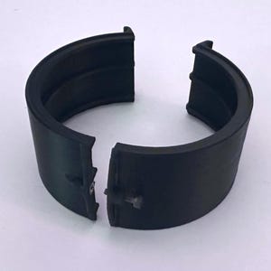 K&ouml;nnte beinhalten: Ein schwarzes, halbkreisf&ouml;rmiges Objekt, das in zwei Teile geteilt ist, mit einer Nut entlang des inneren Umfangs. Das Objekt scheint aus einem gummiartigen Material zu bestehen. Die Teile sind leicht getrennt und zeigen einen kleinen Verbinder.