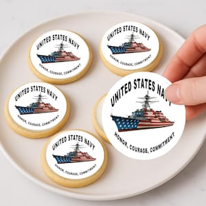 May include: Round cookies with the text "UNITED STATES NAVY" and a ship graphic in red, white, and blue. The cookies also have the words "HONOR, COURAGE, COMMITMENT" in black. Several cookies are arranged on a white plate.