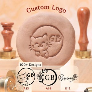 May include: A custom logo stamp with a cat design and the letters "GB" engraved on a circular surface. The stamp is made of a light brown material and includes a wooden handle. The image also shows other stamp designs and the text "Custom Logo" and "100+ Designs".