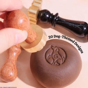 May include: A collection of dog-themed wax seal stamps with wooden handles and brass stamp heads. One stamp is pressed into a brown wax seal, displaying a dog silhouette within a circle. The text "20 Dog-Themed Designs" is visible.
