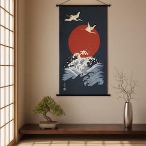 Puede incluir: Colgante de pared de estilo japonés con un sol rojo, grullas blancas y olas azules del océano. La obra de arte se exhibe en una habitación minimalista con un bonsái y un jarrón plateado. La habitación tiene una estantería de madera y un suelo de tatami.