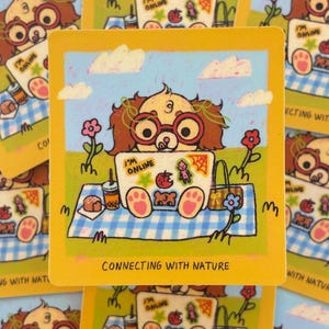 May include: A collection of square cards featuring a cartoon dog wearing glasses and using a laptop on a picnic blanket. The laptop displays the words "I'M ONLINE". The cards have a yellow border and the text "CONNECTING WITH NATURE".