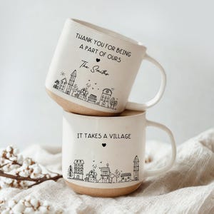 May include: Two stacked ceramic mugs with a cream-colored exterior and a tan base. The top mug reads "THANK YOU FOR BEING A PART OF OURS" with "The Smiths" below. The bottom mug says "IT TAKES A VILLAGE". Both mugs feature a black line drawing of a village.