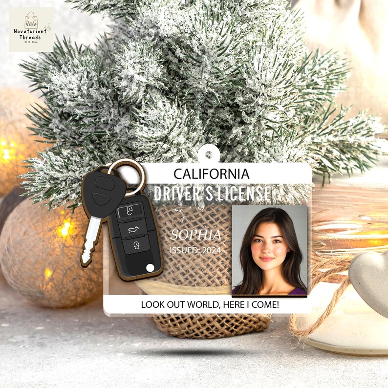 May include: A personalized California driver's license ornament featuring a photo of Sophia, issued in 2024. The ornament includes a car key and the text "Look Out World, Here I Come!" The background includes a Christmas tree.