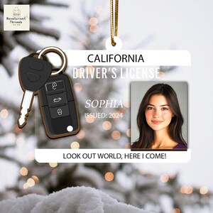 May include: A clear acrylic ornament shaped like a California driver's license, featuring a photo of a woman named Sophia. The ornament includes a car key and the text "LOOK OUT WORLD, HERE I COME!"