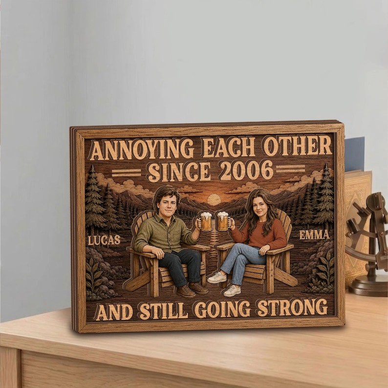 May include: A rectangular wooden sign featuring a carved illustration of two people sitting in chairs, holding beer mugs, with a forest background. The text reads: ANNOYING EACH OTHER SINCE 2006, LUCAS, EMMA, AND STILL GOING STRONG in dark brown lettering.