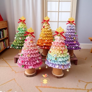 Op de afbeelding: Een verzameling van vijf handgemaakte gehaakte kerstbomen in verschillende kleuren, waaronder groen, roze, oranje, regenboog en paars. Elke boom is versierd met decoratieve elementen en bekroond met een gouden ster en een rode strik. De bomen staan op houten voetstukken.