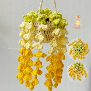 May include: A handmade crochet hanging basket with yellow and cream-coloured wisteria-like flowers. The basket is suspended by a cream-coloured rope. The design includes the text "Designed by koko crochet".