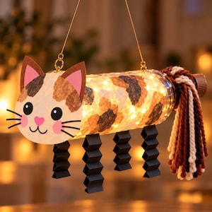 May include: A hanging cat-shaped lantern crafted from a clear plastic bottle, featuring a calico-patterned paper wrap, internal warm LED string lights, black accordion-folded paper legs, and a thick, multi-coloured yarn tail attached to the bottle cap.