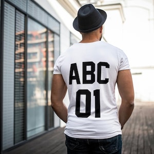 May include: A white t-shirt with black text on the back that says "ABC 01".