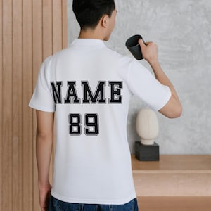 May include: White polo shirt with black text on the back that says "NAME 89".