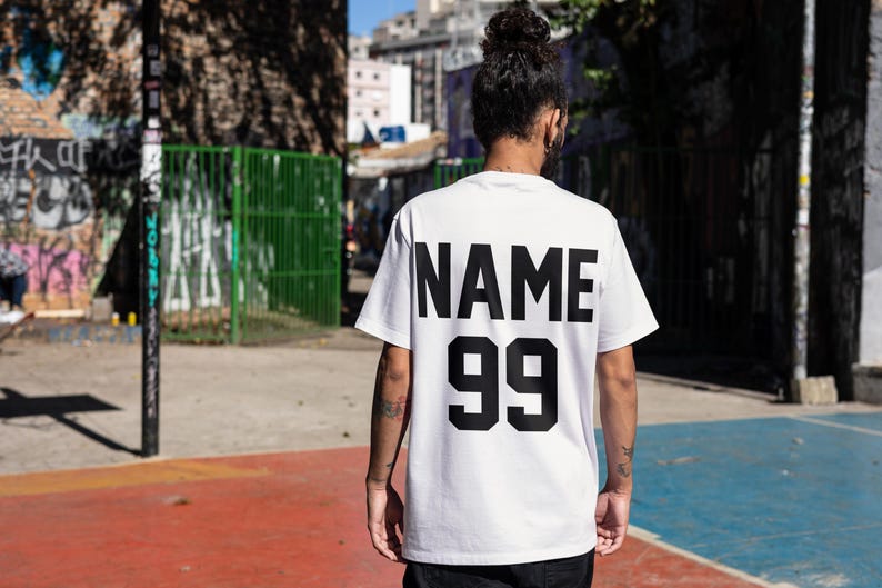 May include: White t-shirt with black text on the back that says "NAME 99".