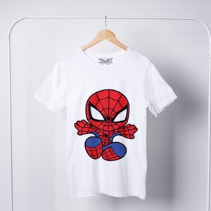 May include: White t-shirt with a cartoon image of Spiderman in a red and blue suit. The image shows Spiderman in a jumping pose with his arms outstretched.
