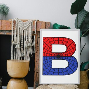 May include: A framed print of the letter "B" with a red and blue spiderweb design. The letter is white and the spiderweb is black.