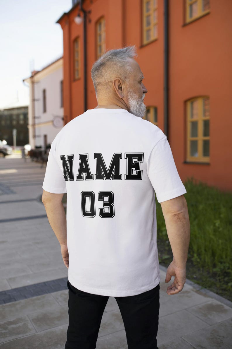 May include: White t-shirt with black text on the back that says "NAME 03".