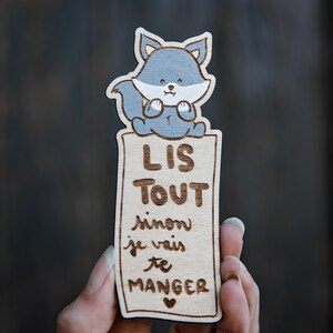 Peut inclure: Un marque-page en bois avec une illustration de loup de dessin animé et le texte "LIS TOUT sinon je vais te MANGER".