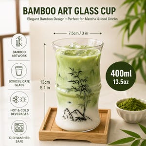 May include: A clear borosilicate glass cup with a bamboo-shaped silhouette, featuring a black ink illustration of bamboo stalks and mountains. The cup holds 13.5 oz, measures 3 inches in diameter and 5.1 inches in height, and contains a green matcha drink.