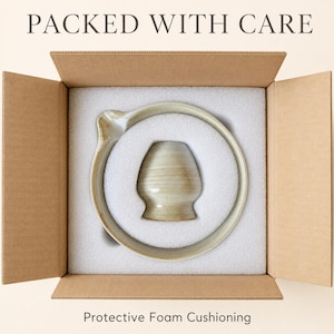 May include: A beige ceramic bowl with a side spout and a matching beige ceramic cup nestled inside a cardboard shipping box with white protective foam cushioning. The text PACKED WITH CARE and Protective Foam Cushioning is visible.