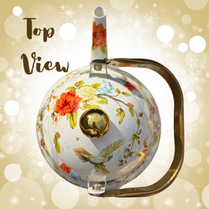 Pu&ograve; includere: Una teiera bianca con un design floreale con fiori rossi, gialli e blu e un uccello. La teiera ha un manico e un beccuccio dorati, con le parole "Top View" in un carattere decorativo.