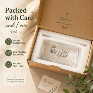 May include: A clear glass cup with a black bamboo illustration inside a brown cardboard box with white foam padding. The box lid features the text "Thank you ENJOY YOUR TEA RITUAL" and the side text "Packed with Care and Love".