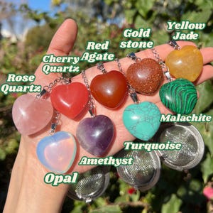 May include: A set of nine heart-shaped crystal tea infusers, each with a different gemstone: rose quartz, cherry agate, red agate, amethyst, opal, turquoise, malachite, yellow jade, and gold stone.