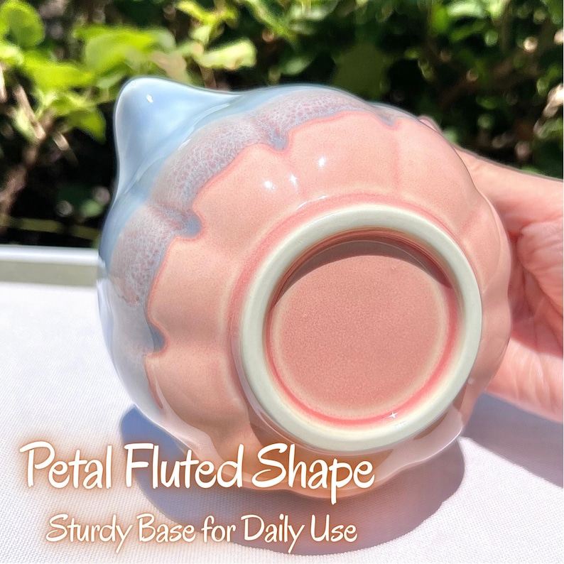 May include: A ceramic pitcher with a petal fluted shape, featuring a gradient of soft pink and light blue glaze. The base is circular and sturdy, with a smooth, matte pink finish. The text "Petal Fluted Shape" and "Sturdy Base for Daily Use" is visible.