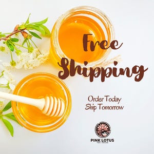 May include: Two glass jars filled with golden honey, one with a wooden honey dipper. The words "Free Shipping" are displayed in a brown script font. White flowers and green leaves are arranged around the jars. The Pink Lotus Tea House logo is at the bottom.