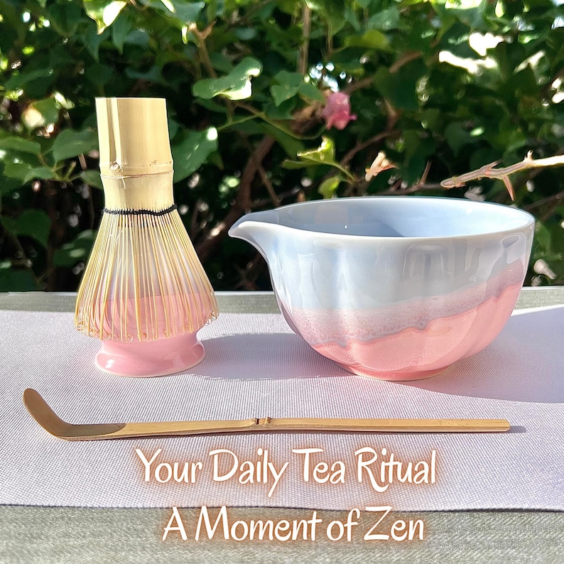 May include: A bamboo matcha whisk with a pink base, a ceramic bowl with a white and pink gradient finish, and a long bamboo tea scoop. The text "Your Daily Tea Ritual A Moment of Zen" is printed at the bottom of the image.