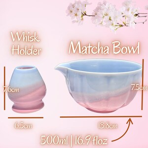 May include: A ceramic matcha bowl and whisk holder with a gradient blue and pink glaze. The bowl features a pouring spout and measures 7.5 cm in height and 13.8 cm in width with a 500 ml or 16.9 fl oz capacity. The whisk holder is 7.6 cm tall and 6.5 cm wide.