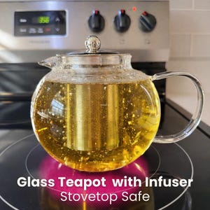 May include: A clear glass teapot with a stainless steel infuser, filled with a golden liquid. The teapot has a rounded shape, a curved handle, and a silver lid. Text on the image reads "Glass Teapot with Infuser Stovetop Safe."