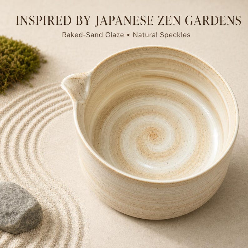 May include: A ceramic bowl with a raked-sand glaze and natural speckles, featuring a small pouring spout. The text reads: INSPIRED BY JAPANESE ZEN GARDENS, Raked-Sand Glaze &bull; Natural Speckles. The bowl has a light beige, swirled finish.
