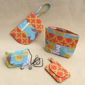 May include: Four different fabric pouches in various sizes and patterns. The pouches are made of a patchwork of orange, yellow, and blue fabrics with geometric and floral designs. The pouches have zippers and some have handles.