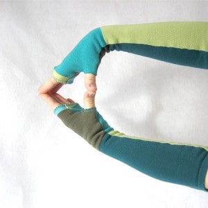 May include: A pair of fingerless gloves with a teal, green, and brown striped pattern. The gloves are made of a soft, stretchy fabric and are perfect for keeping your hands warm while still allowing you to use your fingers.