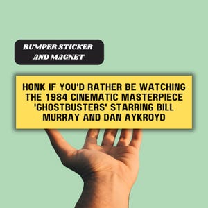 Pode incluir: Adesivo ou ímã amarelo para pára-choques com texto preto que diz "Buzine se você prefere assistir à obra-prima cinematográfica de 1984 'Ghostbusters' estrelando Bill Murray e Dan Aykroyd".