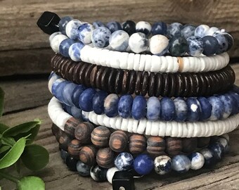 May include: A stack of bracelets made with blue and white patterned beads, brown wood beads, and black beads with metal accents.