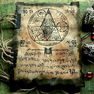 May include: A rectangular book with aged, burnt-edge paper featuring a black ink illustration of a central triangle containing a tentacled creature, surrounded by circular symbols and cryptic script. The binding uses twine and dark leather accents.