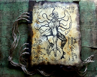 May include: A handmade, aged-looking journal with a detailed pen and ink illustration of a creature with tentacles, surrounded by arcane symbols. The artwork is on parchment-like paper with burnt edges, bound with a dark fabric spine and tied with twine.
