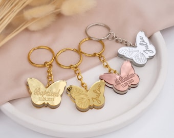 Puede incluir: Tres llaveros de mariposa dorados con grabados personalizados. Los llaveros presentan un diseño de mariposa dorada, oro rosa y plata. Los grabados incluyen "Baptized 11.09.2023", "Julia" y "Mia Bautista 11.09.2023".