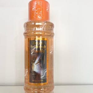 May include: A clear glass bottle with an orange cap and a gold label. The label says "D'Lite Breakthrough Omala" and "Superco Eau de Cologne 75ml Vol."