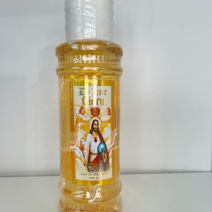 May include: A clear glass bottle with a yellow liquid and a white cap. The bottle has a label with a picture of Jesus Christ and the words "Divine Glory" and "Eau de Cologne 70% Vol."