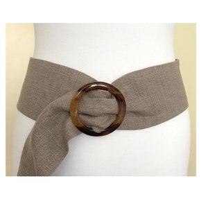 May include: A wide brown linen belt with a large tortoiseshell-colored plastic buckle. The buckle is a simple circle.