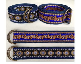 May include: Two blue and gold patterned belts with brass buckles. One belt has a paisley pattern and the other has a geometric pattern.