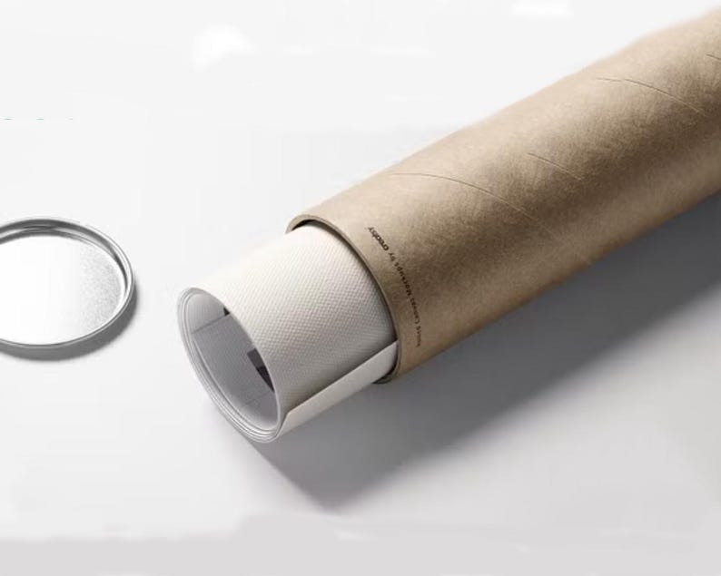 May include: A rolled up print or poster is stored in a brown cardboard tube. The tube has a white label with the text "Assured to Arrive Perfect!" printed on it.
