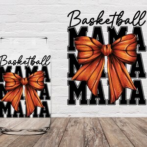 May include: A clear glass tumbler with a design of a basketball-themed bow and the text "Basketball Mama" repeated three times. The background is a white brick wall.