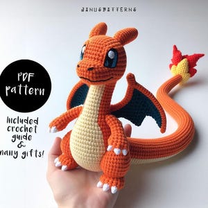 May include: Orange and yellow crocheted plush toy of a dragon with a long tail and blue wings. The toy is being held in a person's hand. The text "PDF pattern" and "Included crochet guide & many gifts!" is visible in the image.