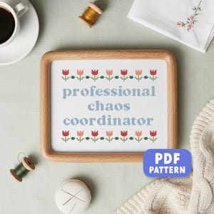 以下が含まれることがあります： 「professional chaos coordinator」の文字が水色で刺繍された額入りのクロスステッチ。赤と桃色のチューリップのような花のデザイン。右下には「PDF PATTERN」のボタンがあります。