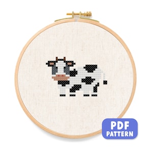 May include: A black and white cow cross stitch pattern in a wooden embroidery hoop. The pattern is in a PDF format.