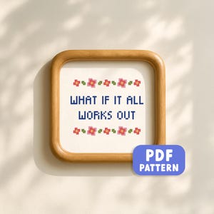 Op de afbeelding: Een ingelijste kruissteek met de marineblauwe tekst "WHAT IF IT ALL WORKS OUT". Het ontwerp bevat rode en roze bloemaccenten. Een blauwe PDF-patroonknop staat rechtsonder. Het frame is van hout.