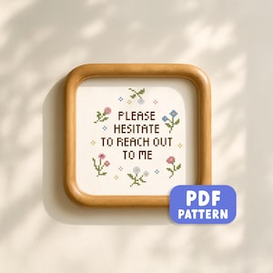 Peut inclure: Un cadre carré en bois contenant un motif de point de croix sur tissu blanc. Le texte PLEASE HESITATE TO REACH OUT TO ME est écrit en lettres marron foncé, entouré de petites fleurs pixelisées roses, bleues et vertes. Étiquette PDF PATTERN.